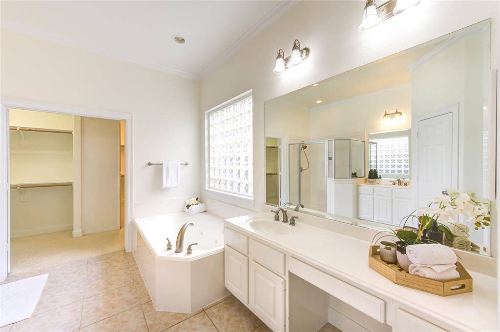 A spa-like en-suite bath with a soaking tub, separate walk-in shower, dual vanities with neutral counters, and updated faucets. A large walk-in closet offers plenty of storage.