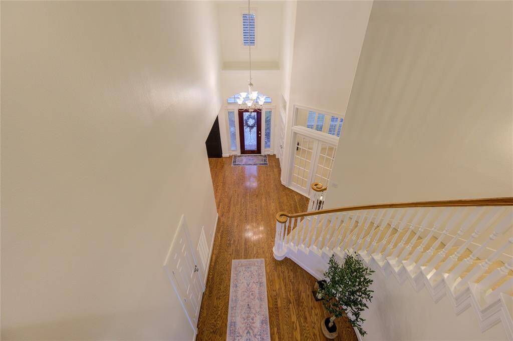 From the second-floor landing, enjoy a stunning bird’s-eye view of the grand foyer, showcasing its soaring ceilings and elegant architectural details. The graceful staircase with wooden handrails adds a touch of sophistication, while the open design highlights the home’s spacious and airy feel. Natural light streams through the large entryway windows, illuminating the space and creating a warm, welcoming ambiance.