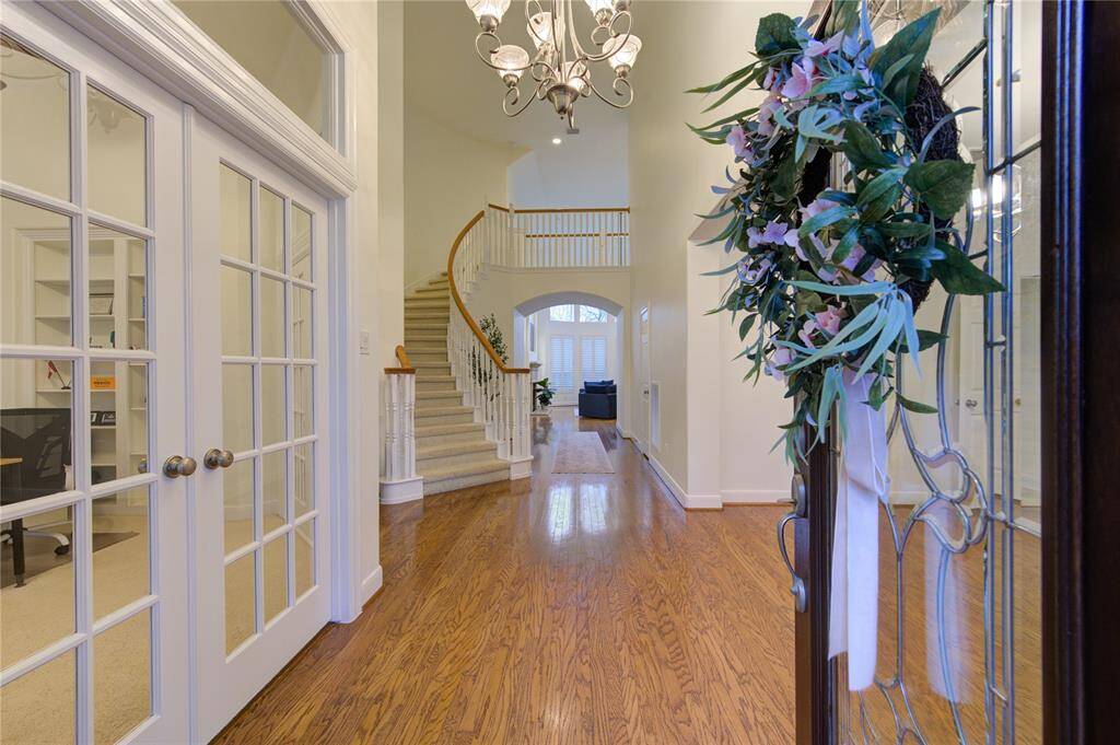 Step into a bright and airy entryway featuring soaring ceilings, elegant wood flooring, and a graceful staircase leading to the second floor.