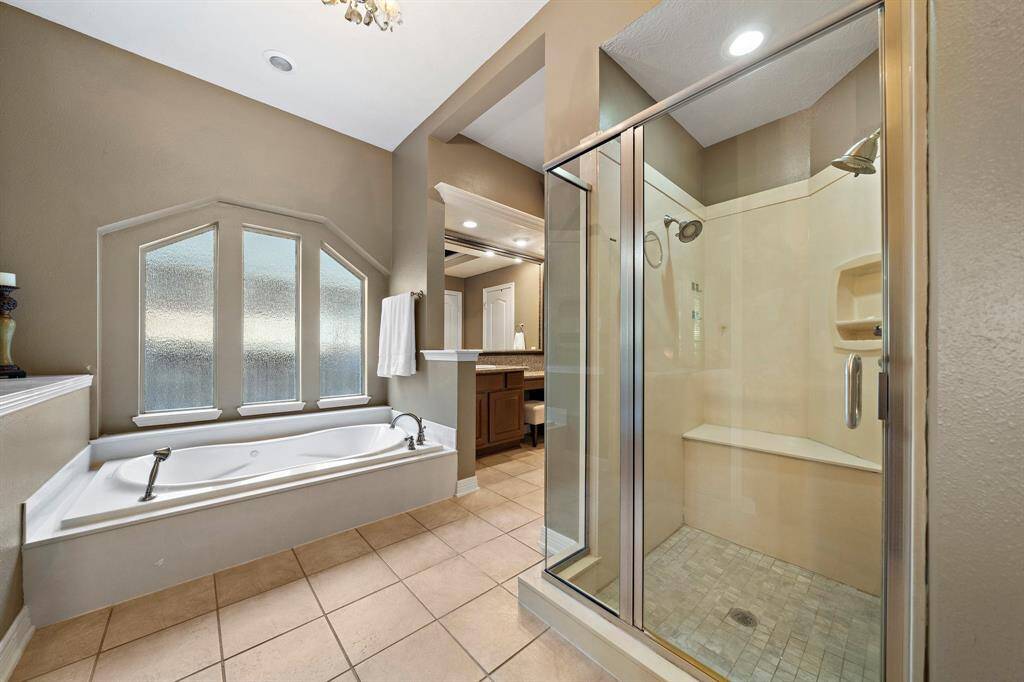 Indulge in ultimate relaxation in the primary ensuite bath, featuring a luxurious soaking tub and a glass-enclosed shower.