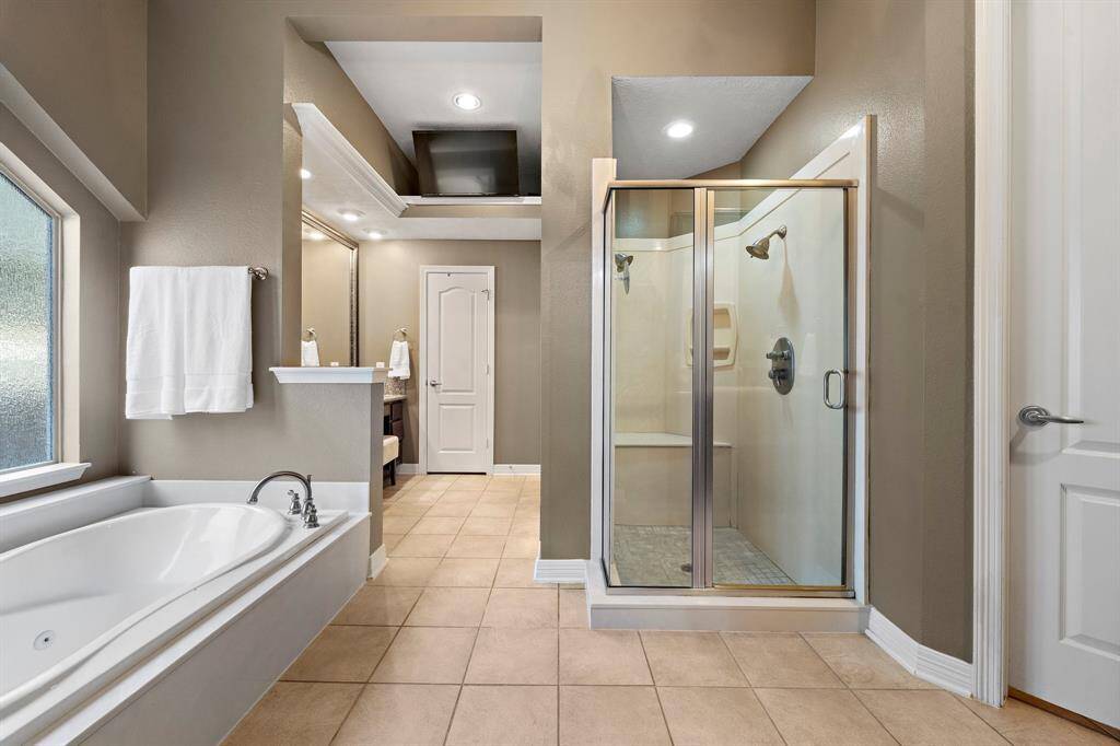 Offering both style and functionality, the sleek primary ensuite is fitted with a jetted tub, a walk-in shower, and dual vanities with custom built-ins.