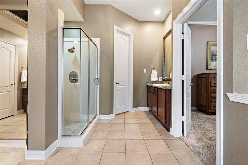 The lavish primary bath showcases classic tile floors, double sinks, and built-in cabinetry for storing your daily essentials.