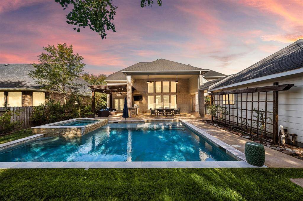 The backyard is a true showstopper, featuring a shimmering saltwater pool with a spa, a covered patio perfect for dining and entertaining, and a pergola seating area for relaxation. Framed by lush landscaping, this private oasis is ideal for enjoying outdoor living at its finest.