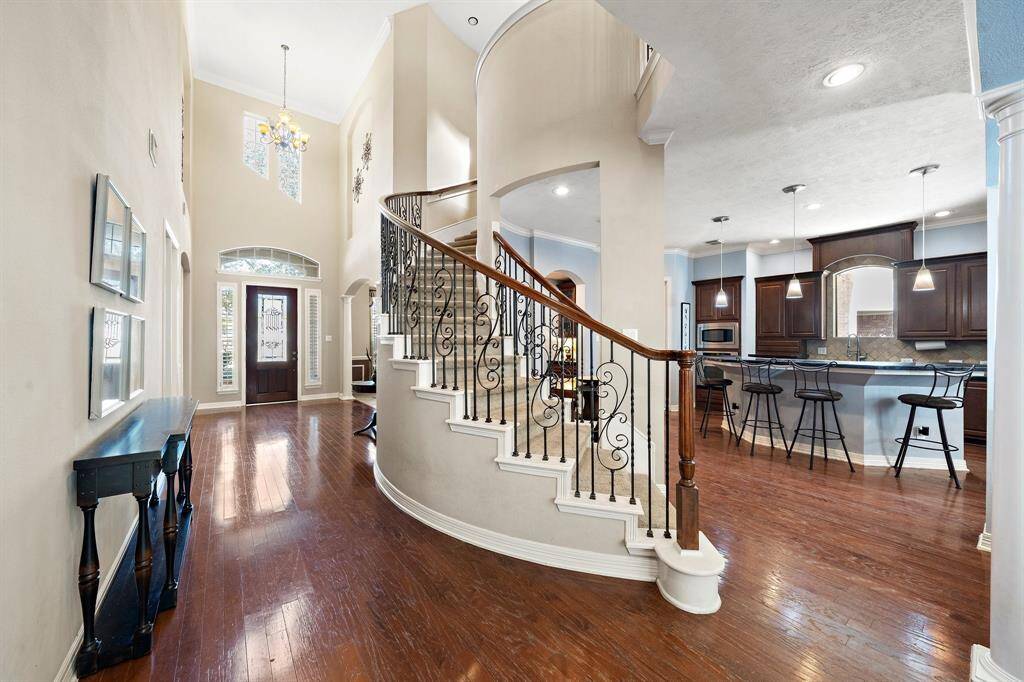 The sweeping staircase, with its curved design, wrought-iron railings, and wood accents, leads to the second-floor living spaces.