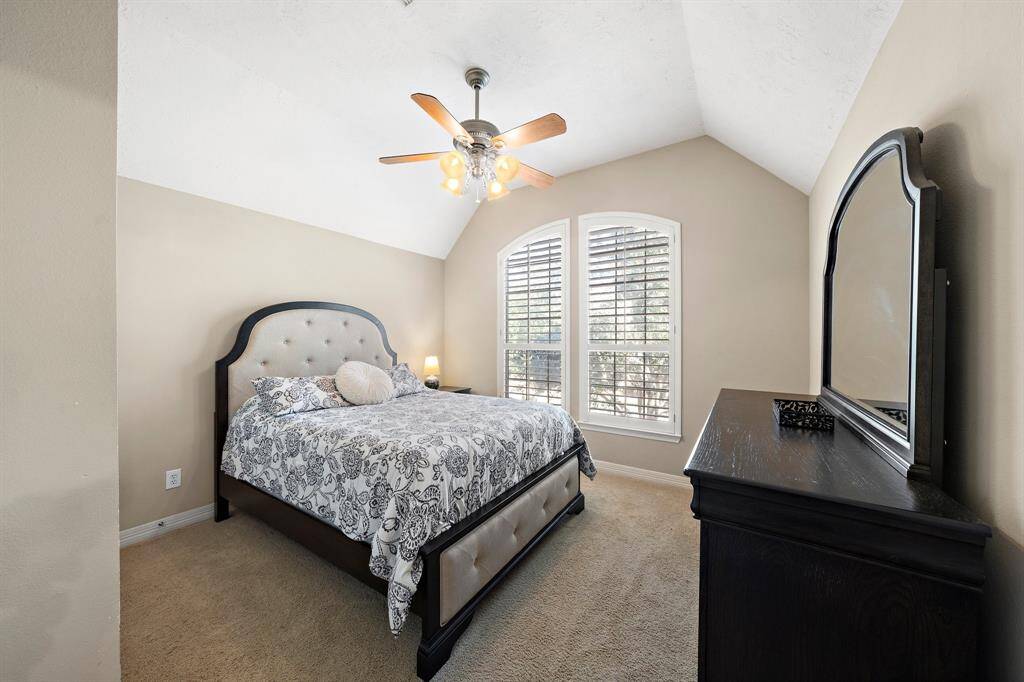 Ideal for a guest suite, the secondary bedroom boasts vaulted ceilings, plush carpeting, and sizable windows that offer neighborhood views.
