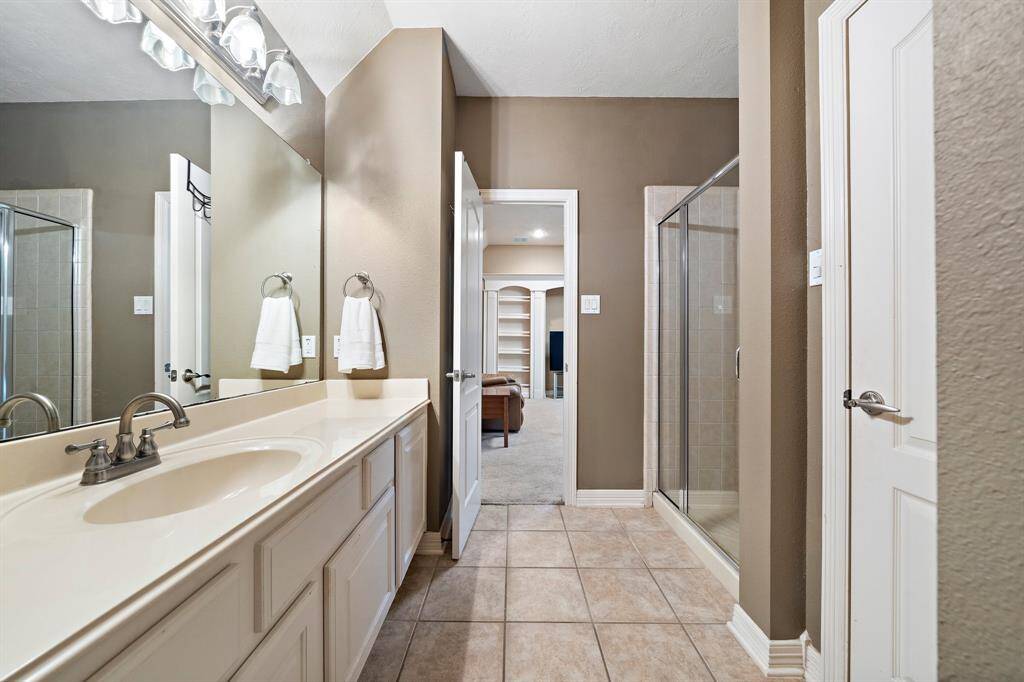 The secondary ensuite bathroom is fitted with a walk-in shower and spacious vanity area with custom built-ins.