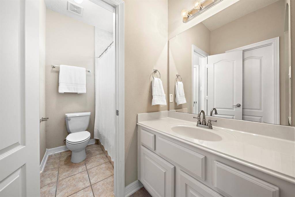 Another secondary bath complete with gleaming tile floors and a vanity area fitted with plenty of built-ins for added convenience.