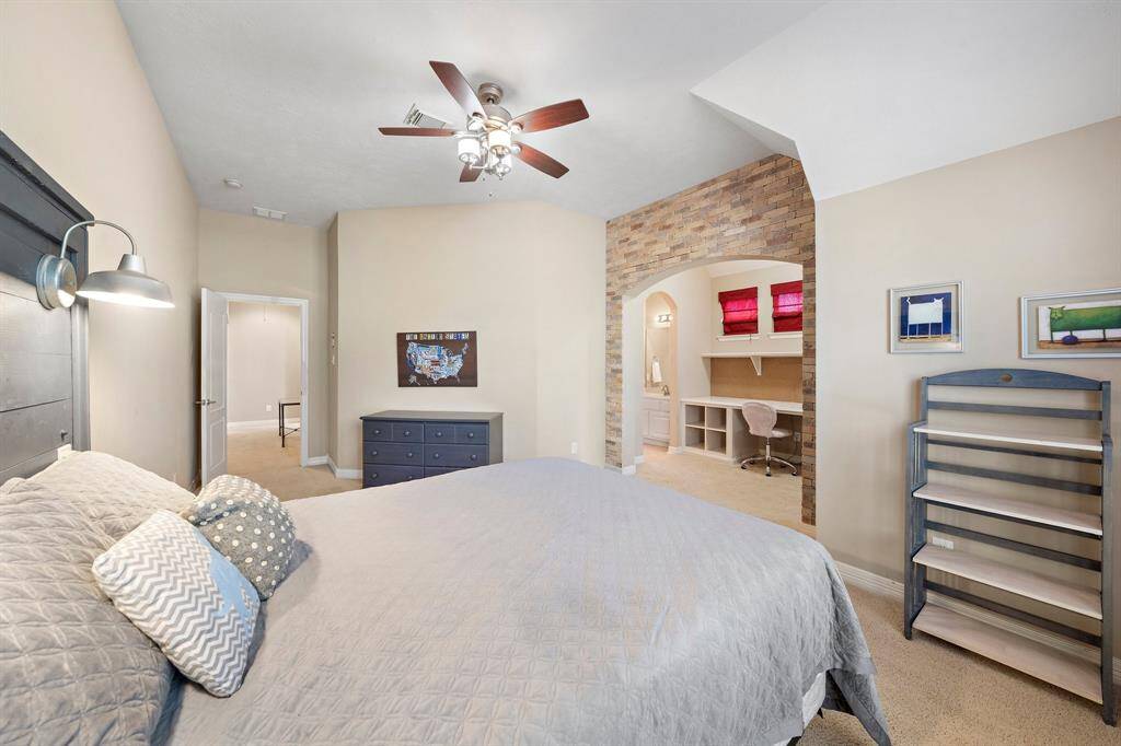 Relax in the generously sized secondary bedroom featuring plush carpet flooring, a functional study nook, a walk-in closet, and abundant space to accommodate large furniture.