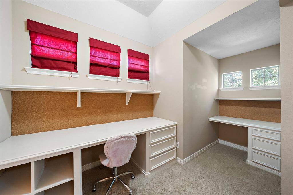The study nook within the secondary bedroom features built-in desks, ample drawer storage, and shelving, offering a functional and private workspace filled with natural light.