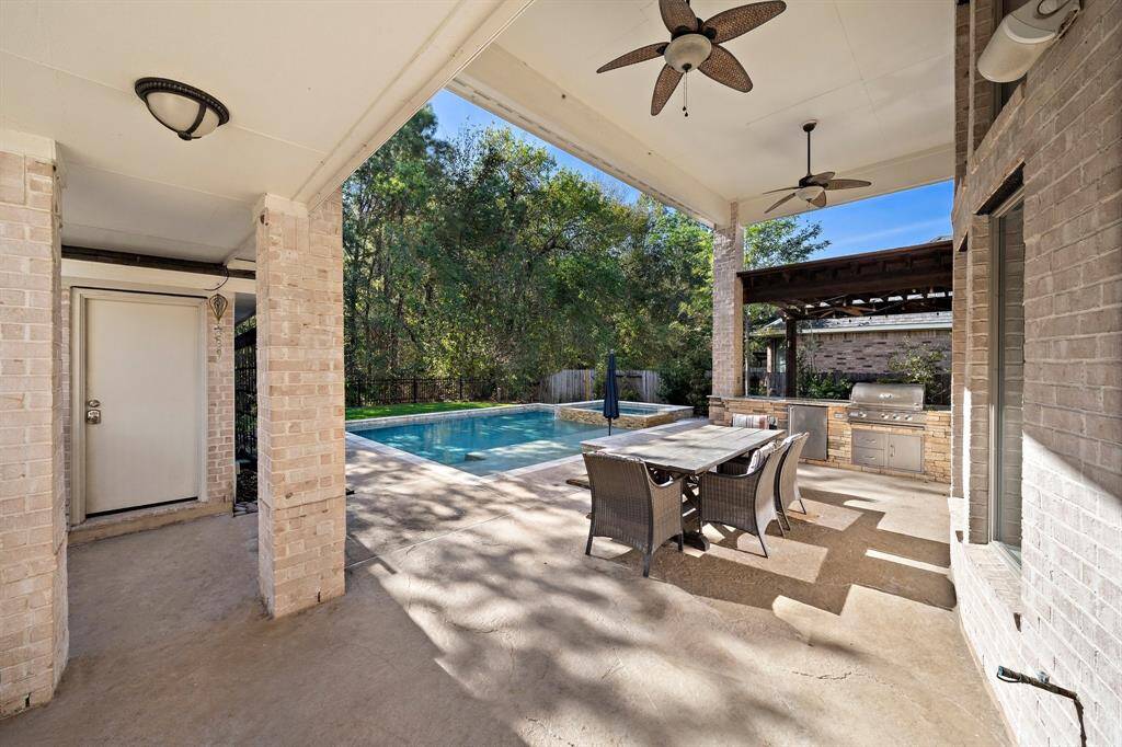 The covered patio offers a seamless outdoor living experience with ceiling fans, ample seating space, and views of the sparkling pool. The adjacent outdoor kitchen with a built-in grill and countertop space makes it perfect for entertaining.