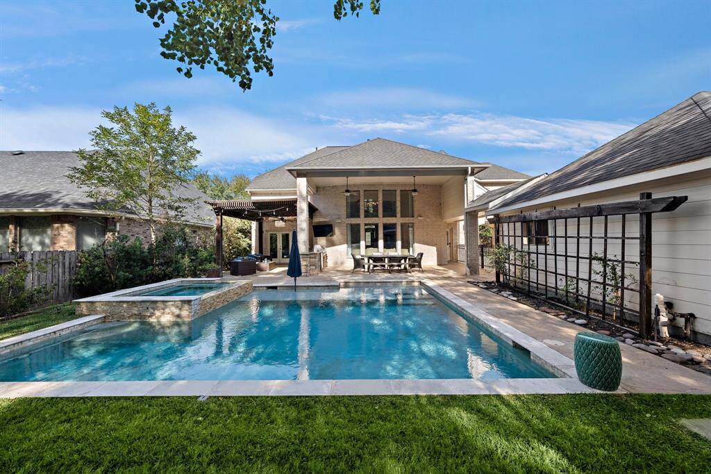 The expansive backyard oasis features a pristine saltwater pool, a relaxing hot tub, a fully equipped outdoor kitchen, and a private seating area, all set against the serene backdrop of a nature preserve.