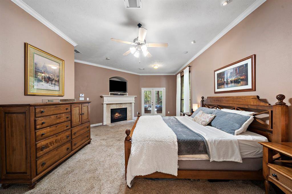 The spacious first-floor primary suite offers a cozy gas log fireplace, dual closets for ample storage, and convenient outdoor access. The ensuite bath features a luxurious soaking tub and a glass-enclosed shower, creating a private retreat for relaxation.