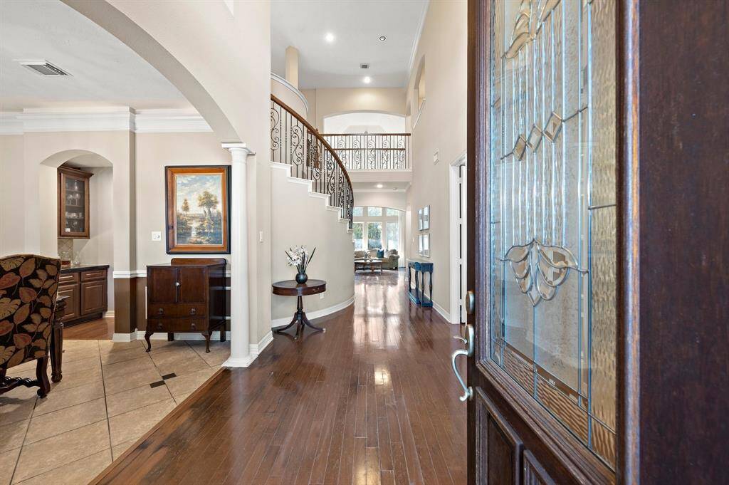 Greet guests in the foyer, showcasing high ceilings and effortless flow to the formal dining area and the executive home office.