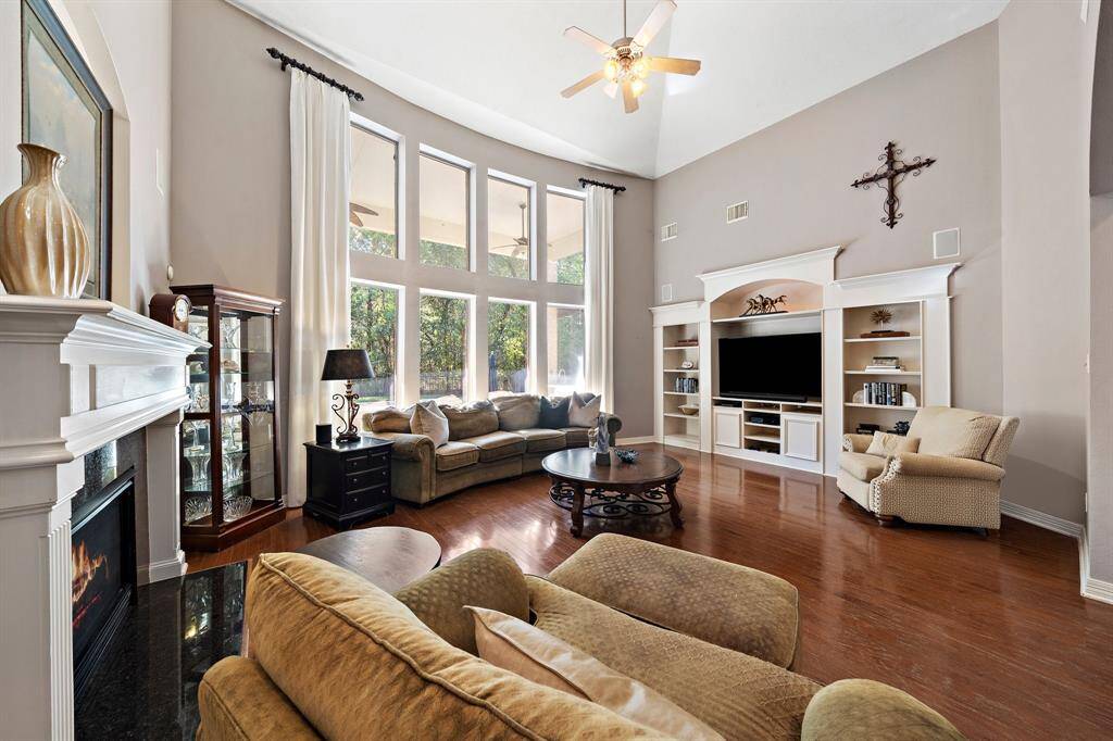 The living area captivates with its soaring ceilings, engineered wood floors, custom built-ins, and open layout, offering both style and versatility for any occasion.
