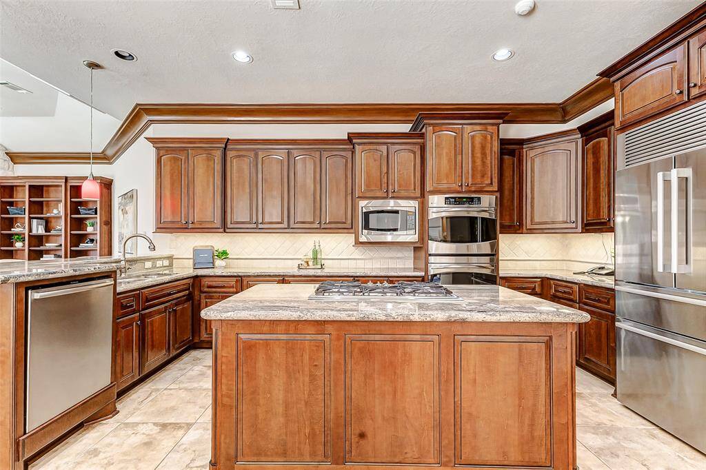 Exquisite chef’s kitchen featuring custom Benedettini maple cabinets in a rich pecan finish, complemented by upgraded Juparana Beach granite countertops and a tumbled marble backsplash. Thoughtfully designed with two pantries, under-cabinet lighting and electrical plugs for a clean backsplash look, a bright and functional island workspace...