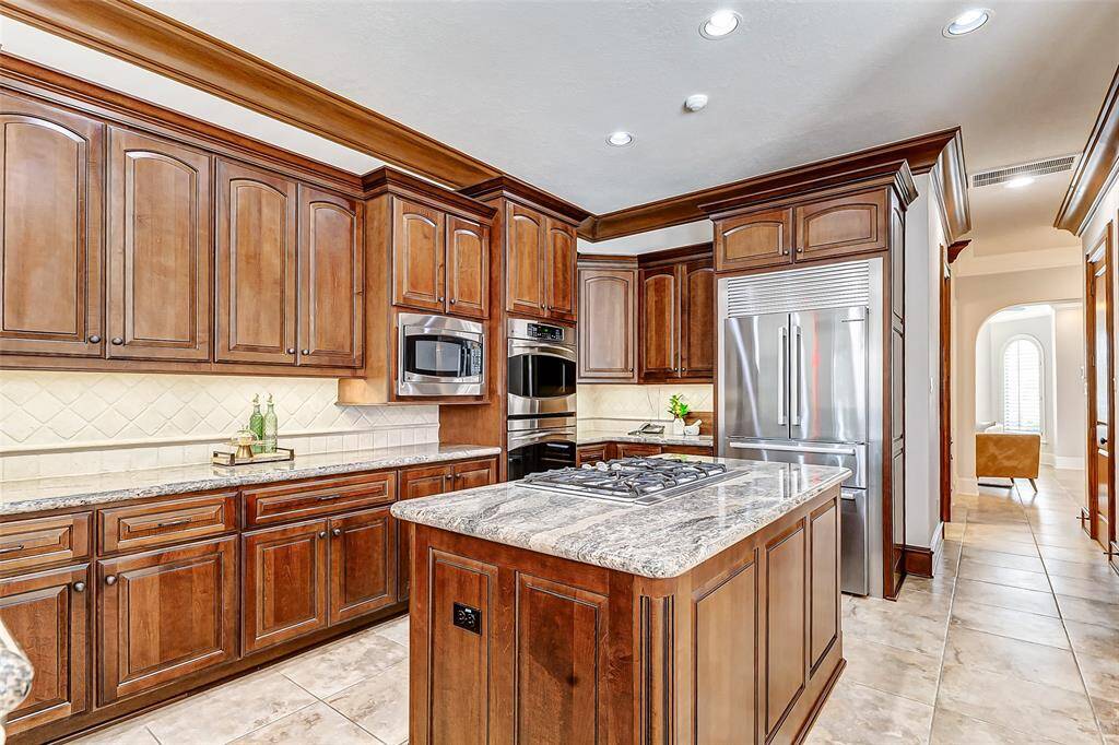 High-end stainless-steel appliances include an upgraded five-burner gas stove with a control lock, GE Profile double ovens with convection and self-cleaning features, a lowered built-in GE profile microwave for easier access, and a raised Bosch dishwasher for added convenience when loading and unloading. The 2021 Bosch built-in refrigerator and 3/4 HP InSinkErator Pro disposal add to the kitchen’s premium features. Pull-out cabinet trays provide smart storage solutions.