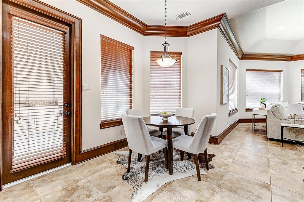 Bright and inviting breakfast room featuring large windows that fill the space with natural light. Elegant accents and crown molding enhance the warmth and charm of the space. Conveniently located just off the kitchen, this cozy dining area offers direct access to the covered patio, outdoor kitchen, and pool area—perfect for seamless indoor-outdoor living and entertaining.