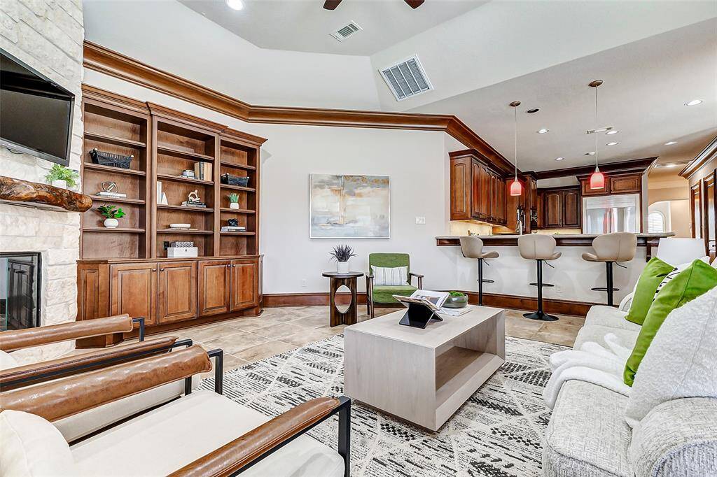 The remote-controlled gas log fireplace with glass doors (installed in 2020) adds warmth and ambiance. Additional features include programmable wall switches for ceiling lights and full CAT 5 wiring for optimal connectivity. The space is open to the breakfast room and kitchen, creating a seamless flow for entertaining and everyday living.