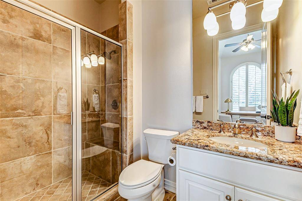 This elegant ensuite bathroom features a spacious walk-in shower with tile surround, built-in bench and a glass enclosure. The vanity showcases a granite countertop with an undermount sink, complemented by brushed nickel fixtures and soft overhead lighting. A large mirror enhances the space, while a neutral color palette creates a warm and inviting atmosphere.