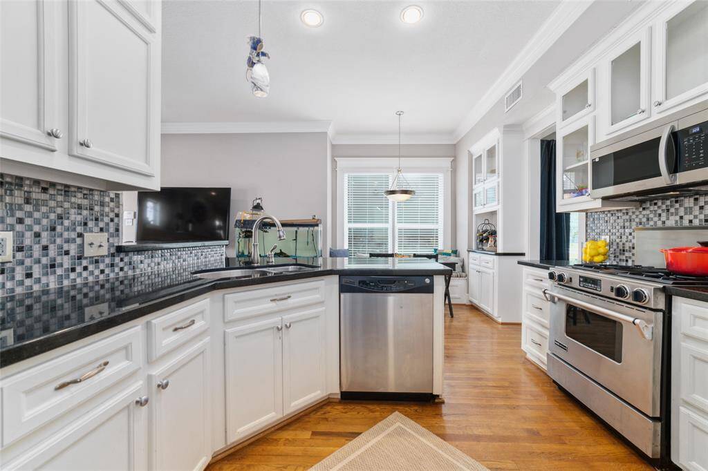 Equipped with an under-mount sink, elegant glass cabinets, a JennAir oven, and a GE dishwasher.