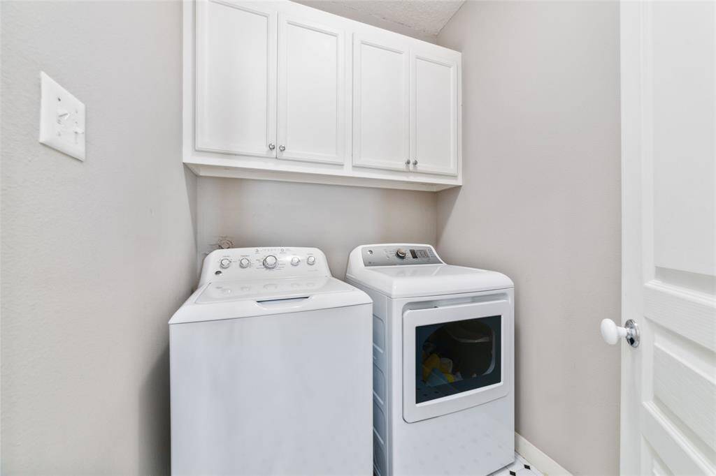 Upstairs laundry room. The washer and dryer will stay with the home for your convenience. Nice storage above.