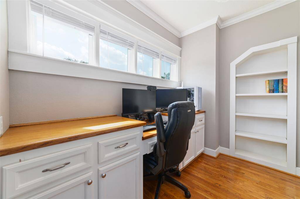 A built-in office desk with two walls of shelving. One of them...
