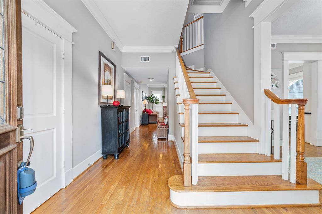 The entryway features a large closet with shelves to the left, complemented by wood flooring and elegant crown molding.