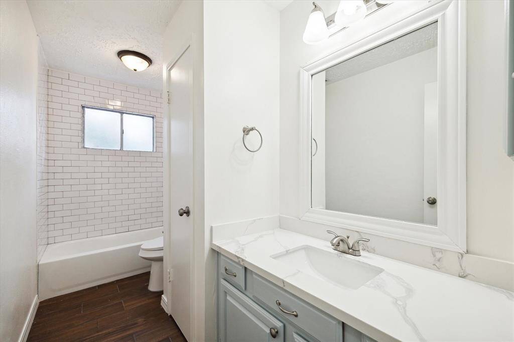 Tasteful updates to the hall bathroom include fresh paint, a refreshed vanity with quartz countertops and new tiling throughout.