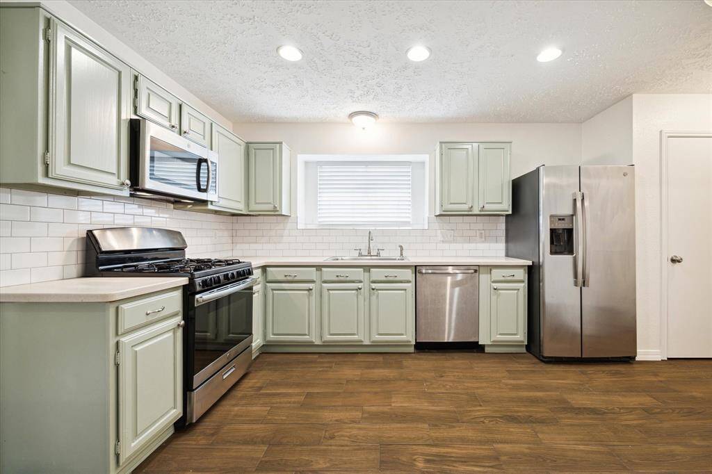Tastefully updated, this kitchen features freshly painted cabinetry, modern subway tile backsplash, sleek stainless steel appliances, and plenty of space for your breakfast table or island.