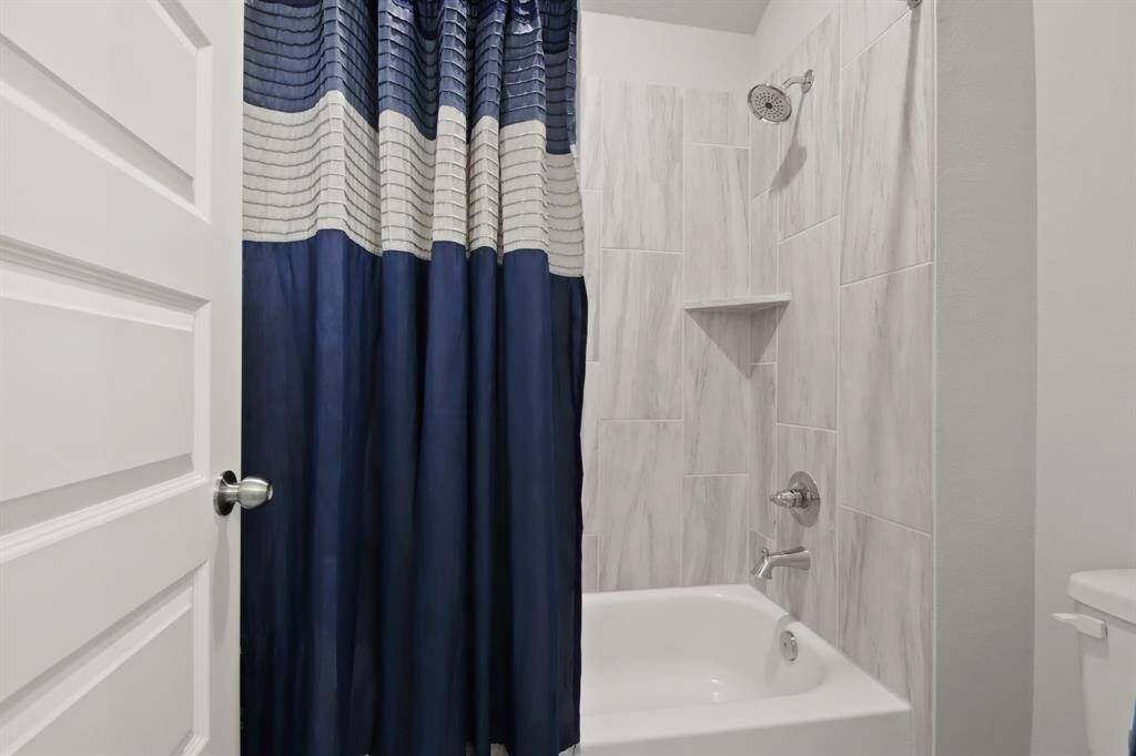 Bathroom three tub with surround tile is clean and bright. Has shelving built in area for added convenience.