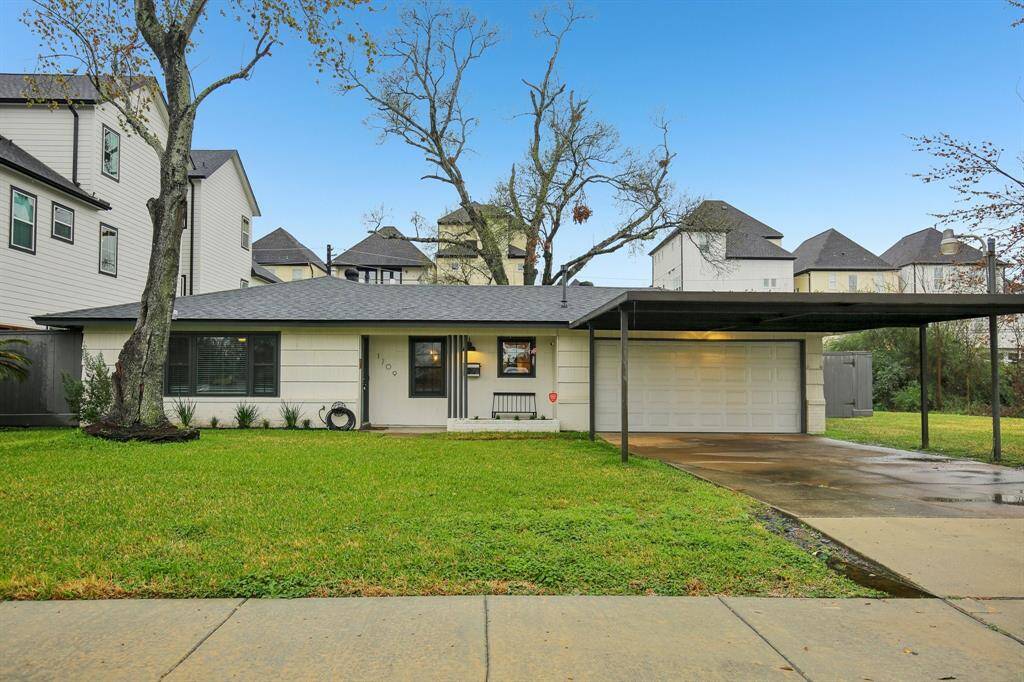 Ranch style home with a modern exterior, featuring a large front lawn and a covered driveway.