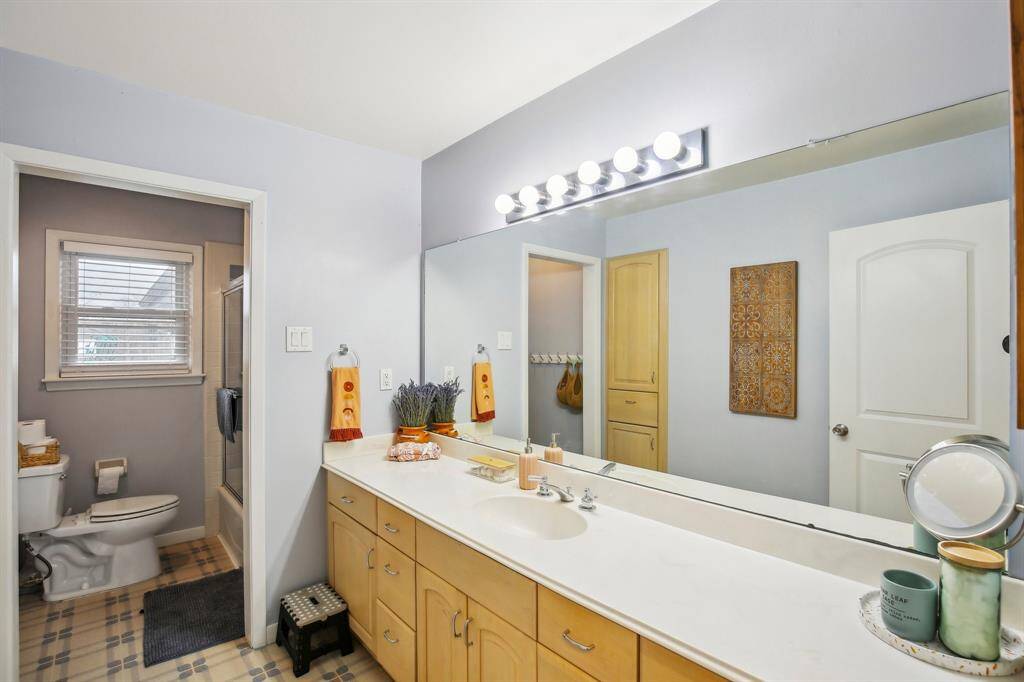 This bathroom features a spacious vanity with bright lighting and ample storage. There is a separate toilet and full bath and shower combo.