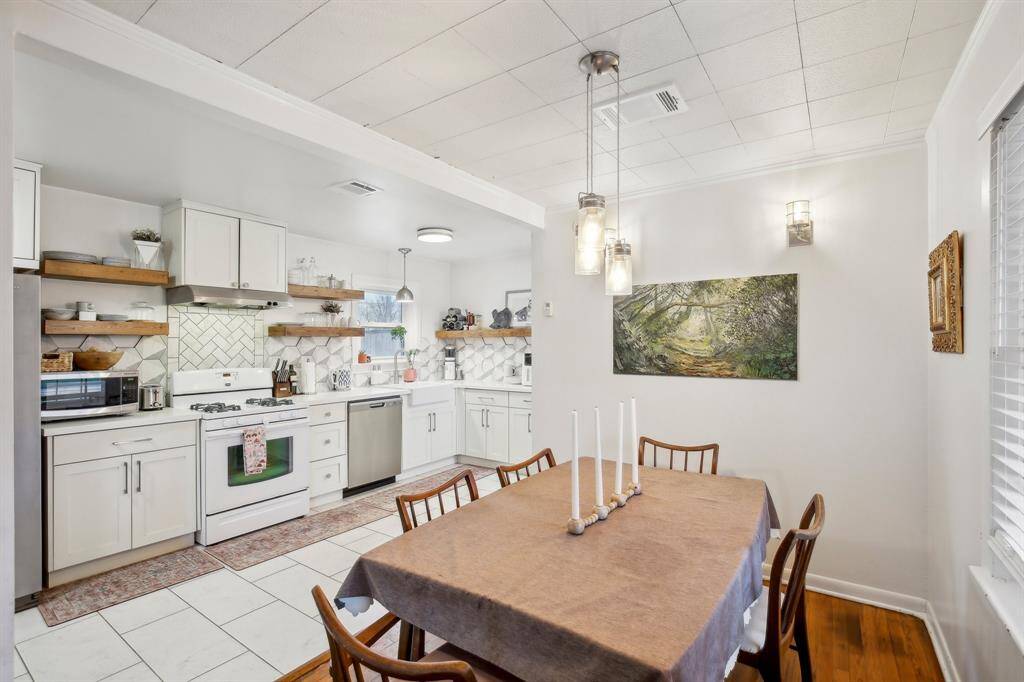 This kitchen was remodeled in 2017.  It has white cabinetry, open shelving, and a modern backsplash. There is a gas stove and quartz countertops.