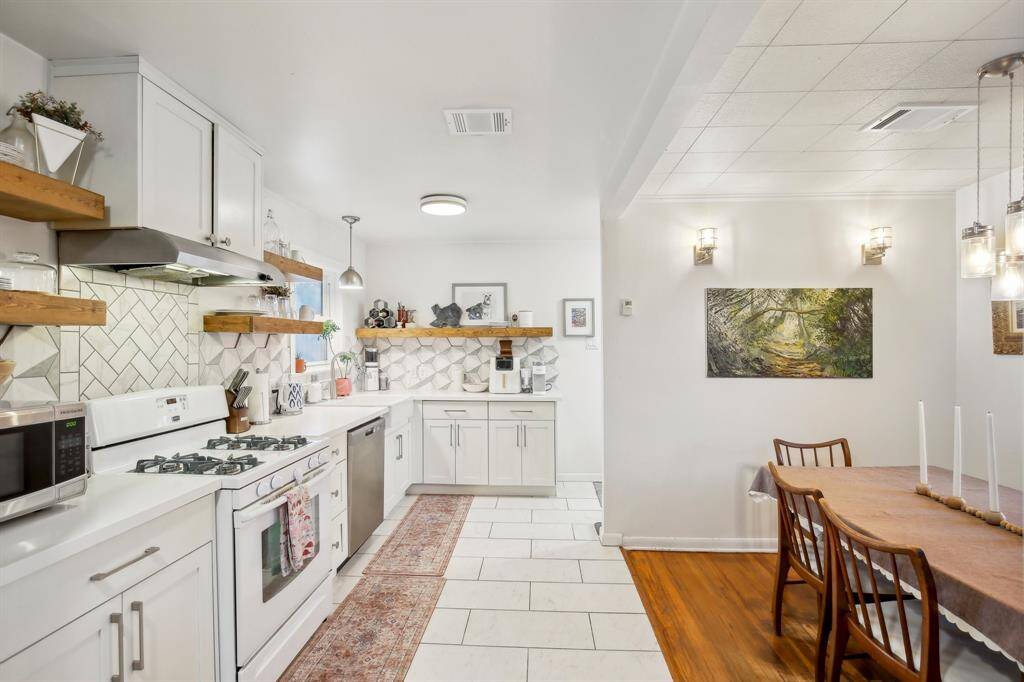 This kitchen was remodeled in 2017.  It has white cabinetry, open shelving, and a modern backsplash. There is a gas stove and quartz countertops.