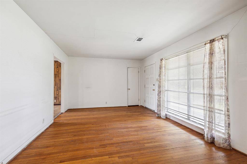Living room with hardwood flooring and large front windows.