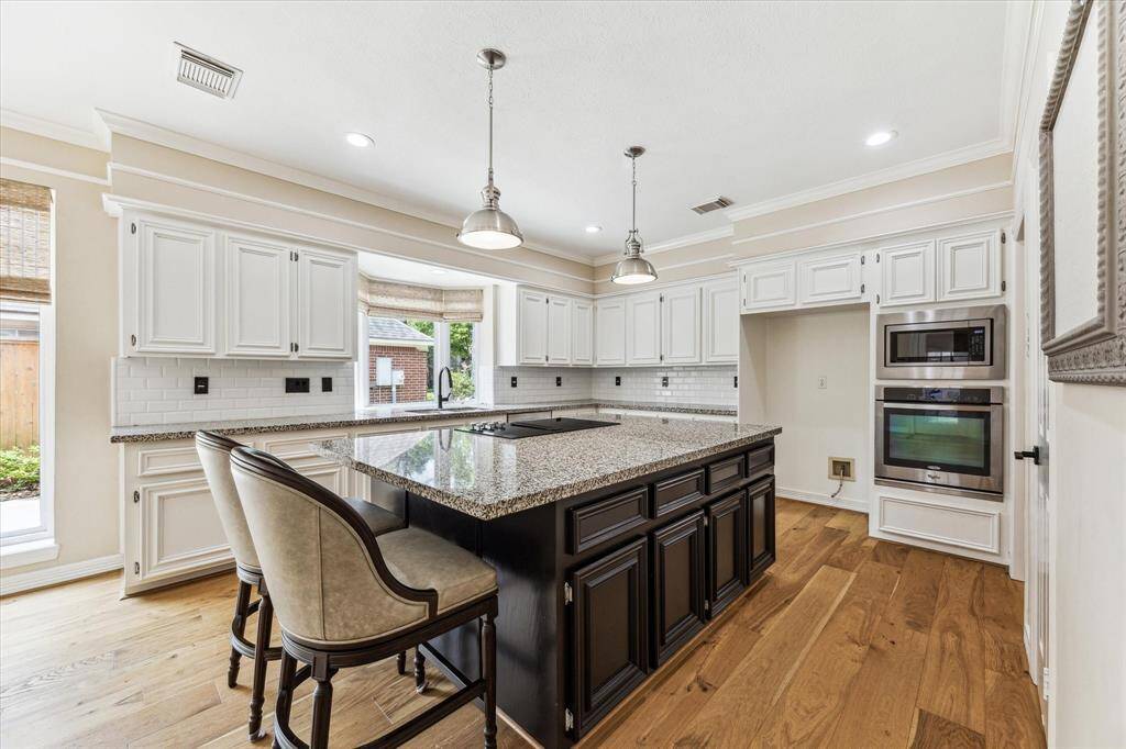 The kitchen, as viewed when entering from the family room. Kitchen features include updated engineered wood flooring, a large island, built-in microwave, a large walk-in pantry and crown and accent molding.