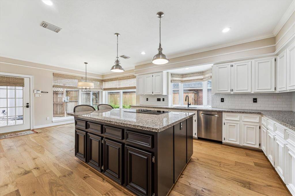 The kitchen, as viewed from the butler's pantry. Features include custom site-built wood cabinetry, slab granite counter tops with subway tile back splash, crown molding, updated lighting, Stainless Steel finish appliances and a large "garden" window behind the sink.