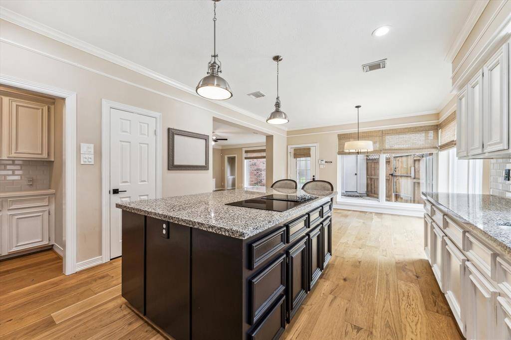 The kitchen design includes a large island with slab granite top, an overhang that accommodates bar stools and a 5-burner smooth surface electric cook top.