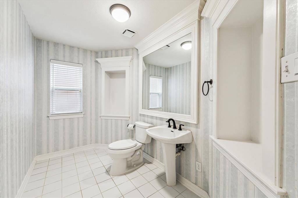 The lower level 1/2 bath features ceramic tile floor, pedestal sink, oversize mirror and dual art niche's.