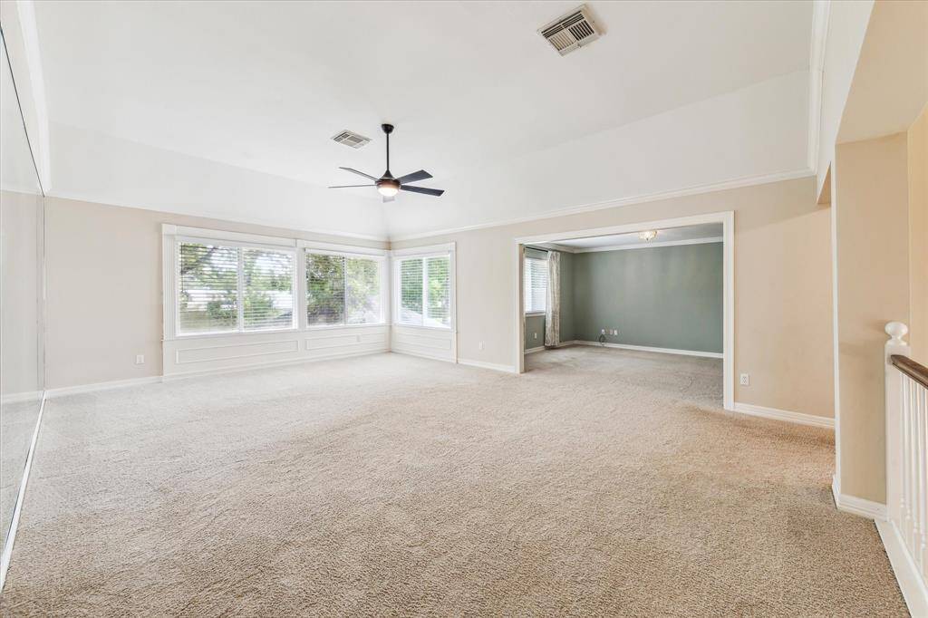 The upper level gameroom features carpet floor, high ceiling, crown molding and mirrored accent wall. The front of the game room is open and looks over the lower level main entry.