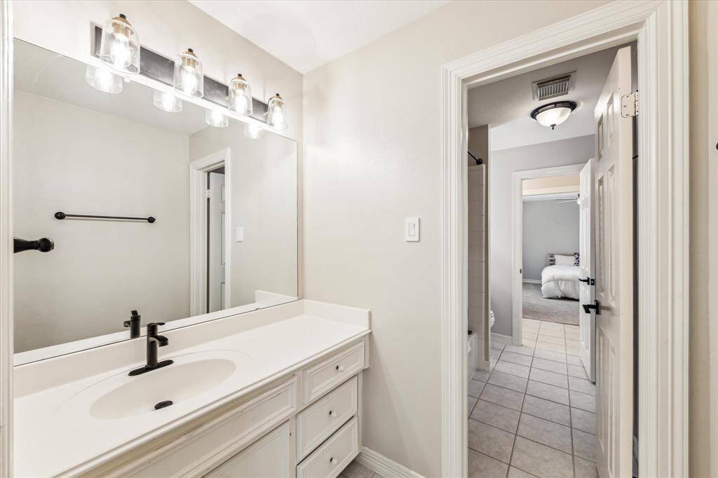 A view of one side of one of the upper level Jack-n-Jill bath rooms. This bath features ceramic tile floor and solid surface vanity top.