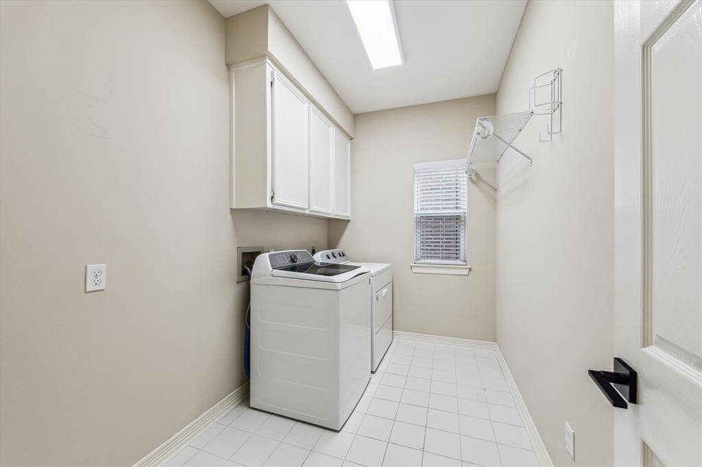 The laundry room has built-in cabinet storage and room for a fridge/freezer.