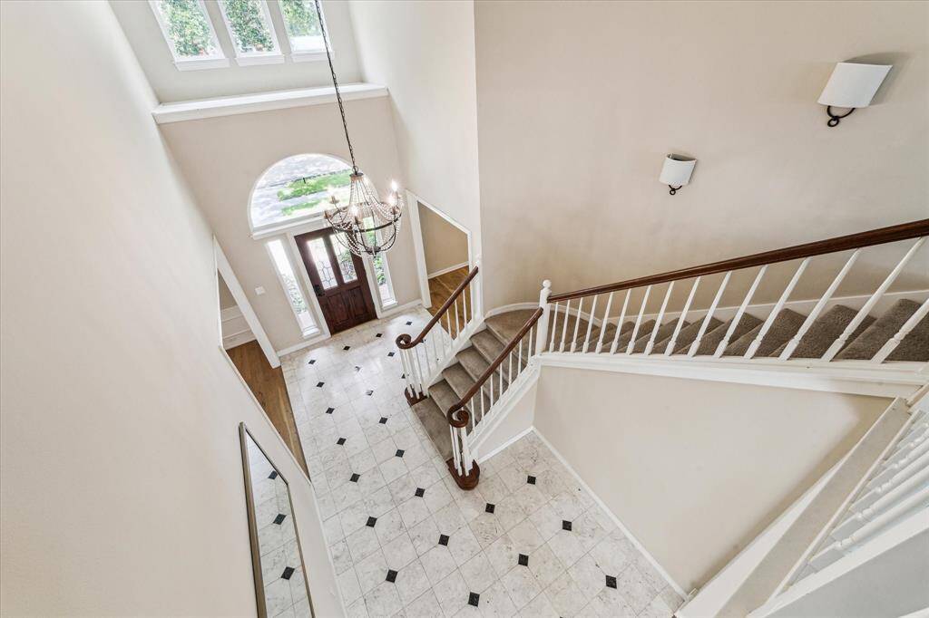 This view of the front entry from the upper level gameroom shows the accented tile entry floor and Mahogany and leaded glass entry door that is accented with an arched transom window and side-light windows.