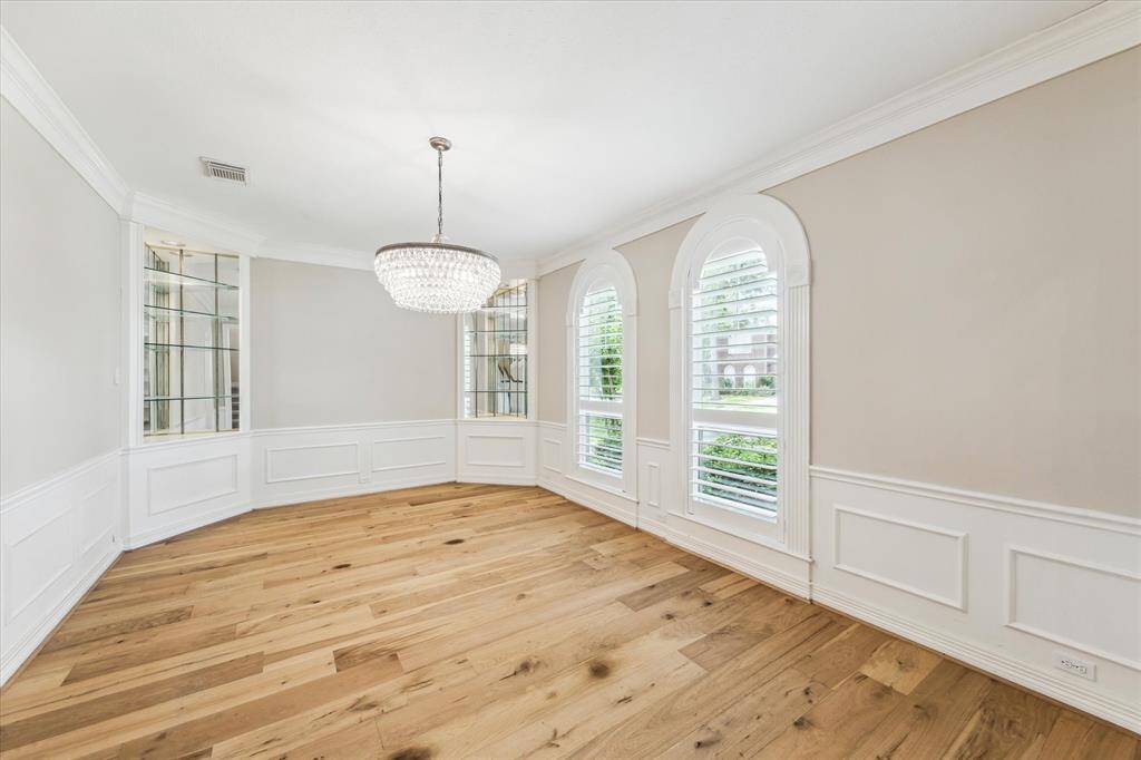 The formal dining room is located directly across from the home office/study at the right of the entry. The dining room features updated engineered wood floor, compound crown molding, double arched windows with coastal shutters, accent wall trim and double corner built-in shelving.