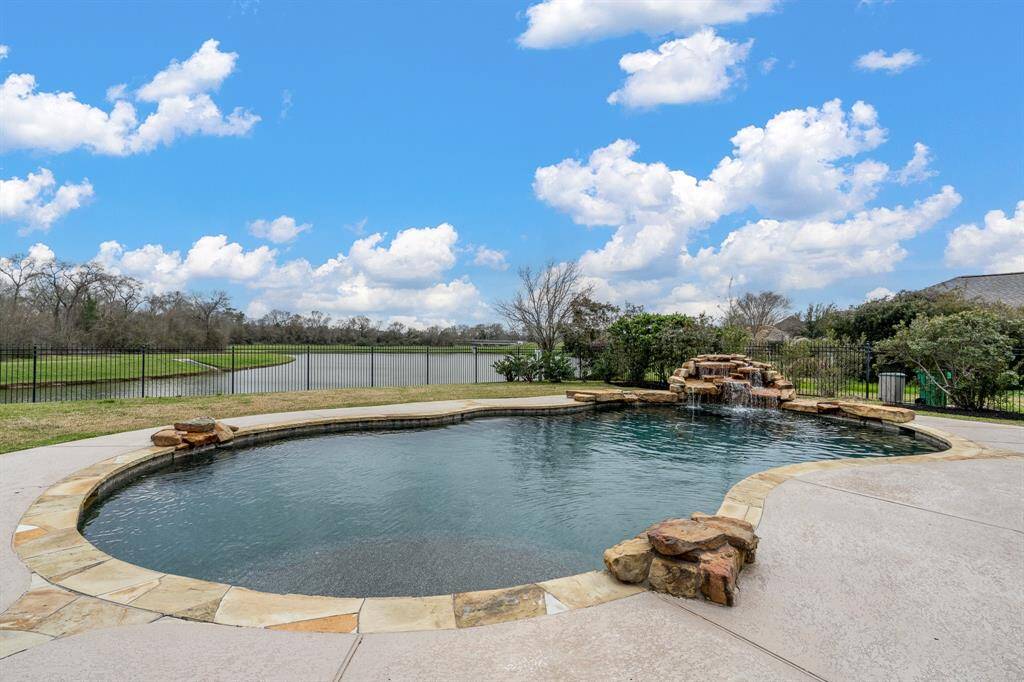 Escape to your private backyard oasis with this stunning waterfront view. This beautifully designed resort-style pool features a natural stone waterfall, creating a serene and inviting atmosphere.