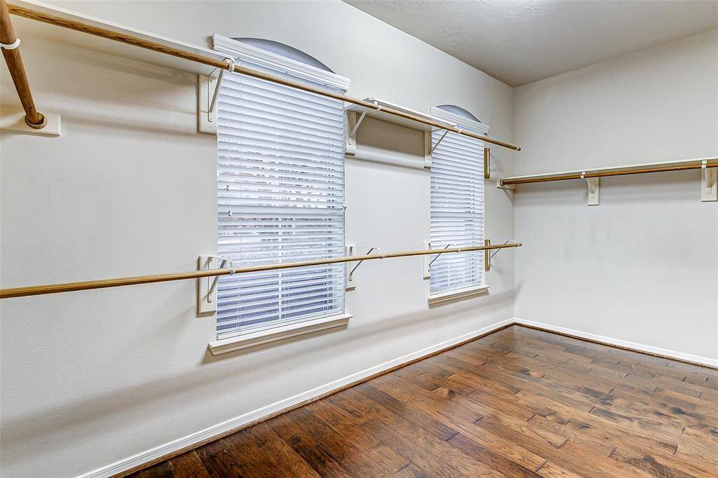 The spacious primary closet offers ample hanging space along with built-in shelving, providing plenty of room for organization and storage.