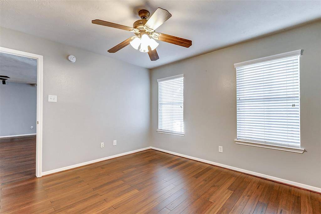 This 4th secondary bedroom includes a walk-in closet, wood floors, neutral paint color, and lighted ceiling fan.