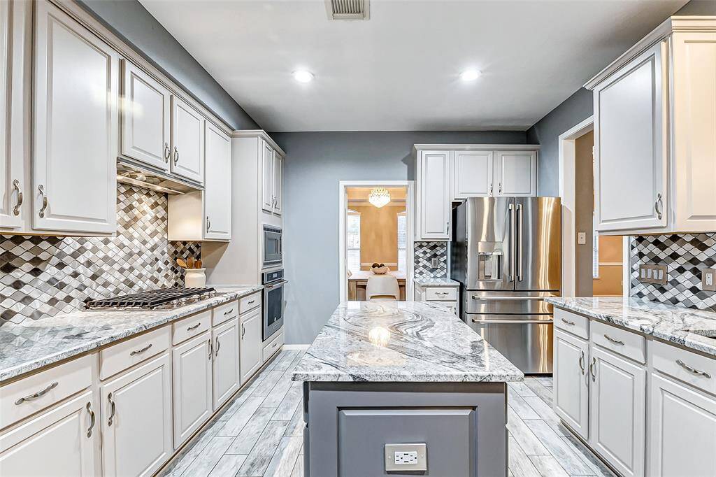 Step into this updated kitchen featuring KitchenAid appliances and Bosch dishwasher, complemented by a gorgeous backsplash.
