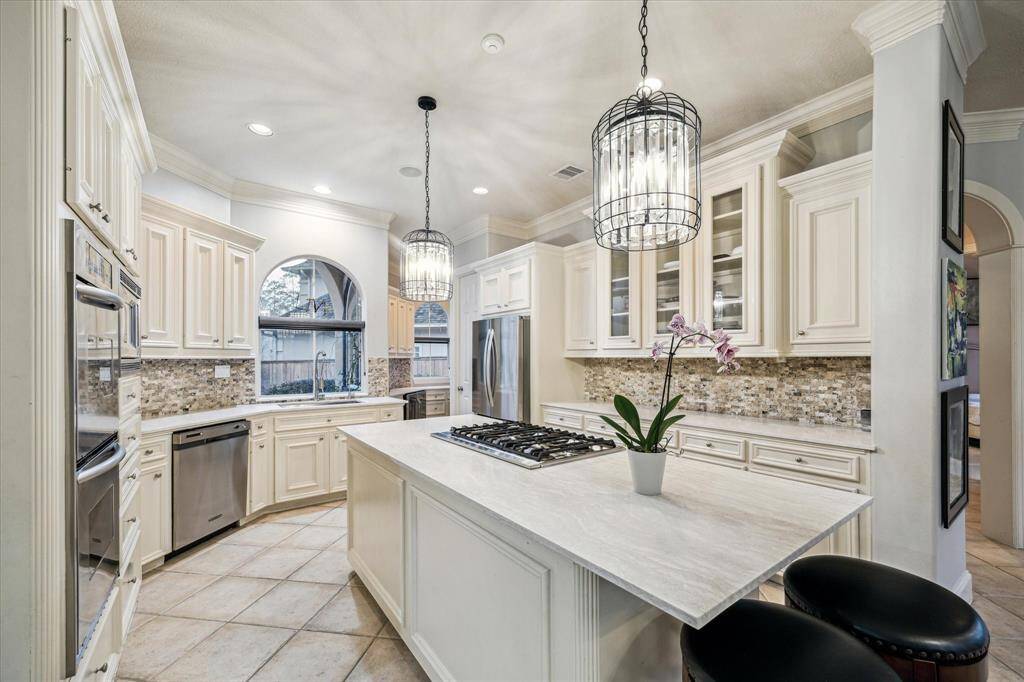 Custom chandeliers hang over the dine-in kitchen island creating bright light and elegance.