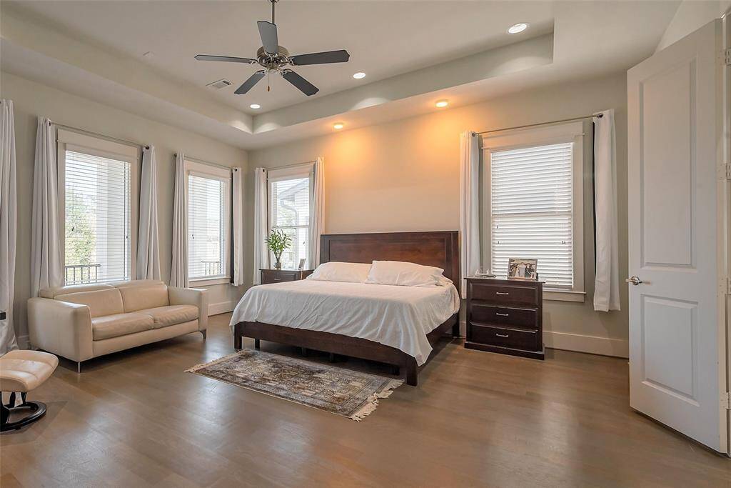 Beautiful spacious primary bedroom with tray ceilings, wood floors